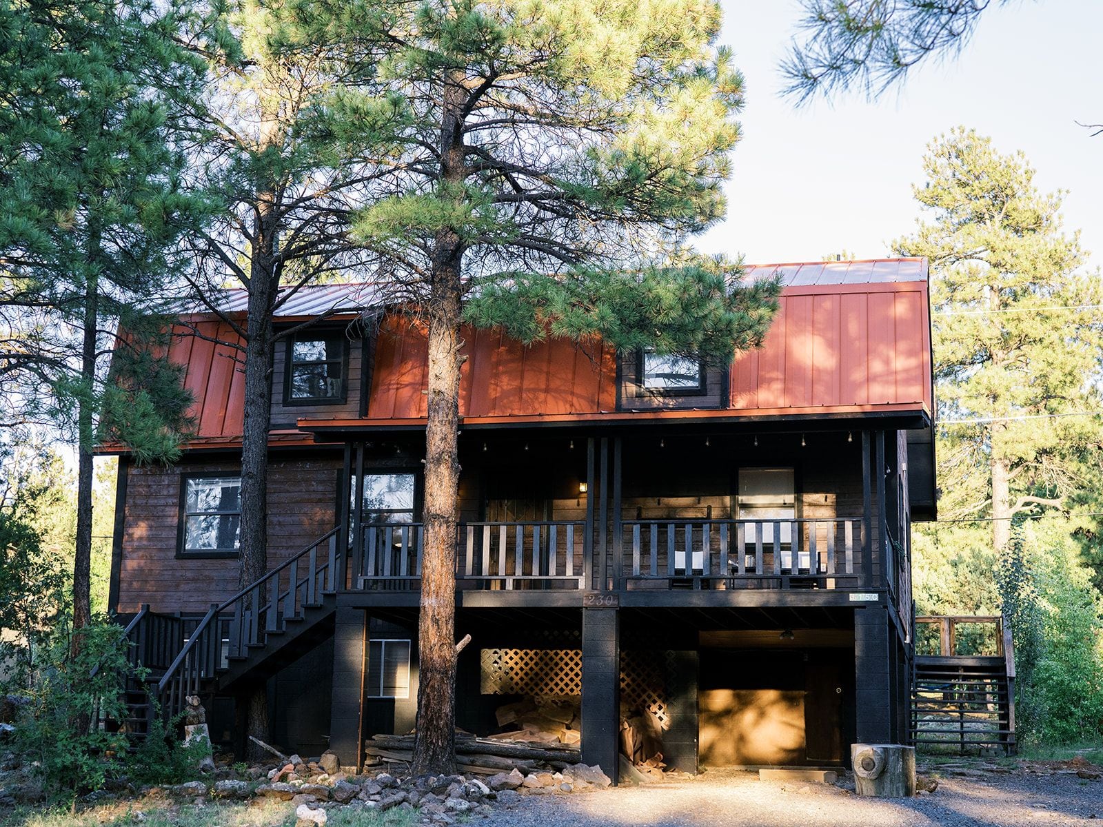A two-story cabin with a wooden exterior, a balcony on the upper floor, and a staircase leading to the entrance.
