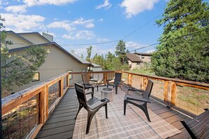 A deck with outdoor furniture and a fire pit, surrounded by a wooden railing.