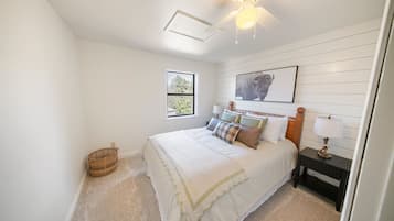 A bedroom with a bed, a nightstand, a lamp, a window, and a ceiling fan.