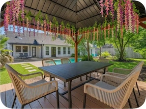 A covered patio with a pool table, chairs, and hanging flowers. - Houston Southwest Oasis – Heater Pool & Game Room (Houston)