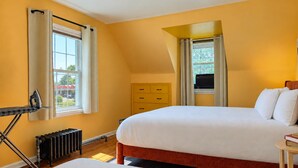 A bedroom with a bed, a radiator, a window with curtains, a dresser, and a small table with books. - Coastal Home | Patio & Firepit | Backyard Games (Merrillville)