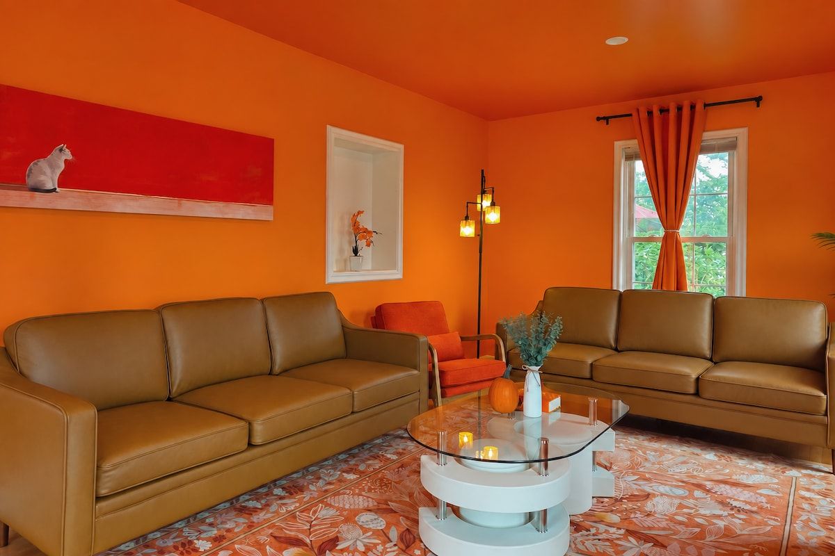 A living room with two brown leather sofas, a glass coffee table, and a red abstract painting on the wall.