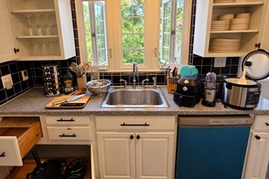 Eine Küche mit Spüle aus Edelstahl, Toaster, Slow Cooker und Geschirrgestell.