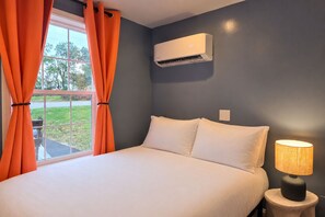 Ein Schlafzimmer mit einem Bett, einer Klimaanlage, einer Lampe und Vorhängen.