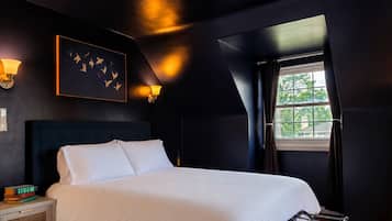 A bedroom with a bed, bedside lamps, a window, and a wall-mounted artwork.