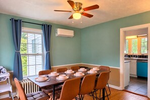 A dining room with a table set for six, a ceiling fan, and a view to the outside.