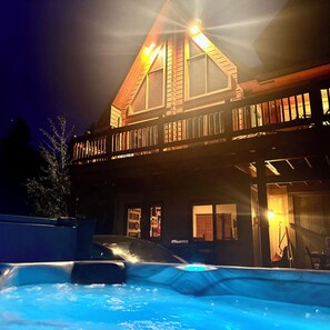 Ein zweistöckiges Gebäude mit Balkon, Schwimmbad und gut beleuchteter Fassade.