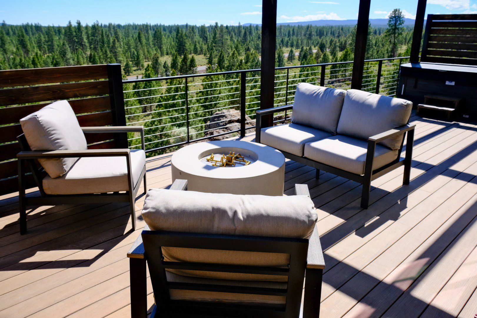 A deck with outdoor furniture, including a sofa and chairs, and a round table with a decorative item.