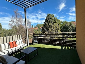 An outdoor patio with a wooden fence, a white sofa with orange cushions, and a grill. - A fully equipped haven of peace, close to downtown Aix-en-Provence, the TGV station, and the airport (Aix-en-Provence)