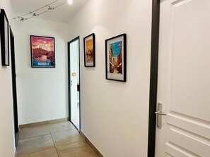 A hallway with framed pictures on the walls, a door on the right, and a tiled floor. - A fully equipped haven of peace, close to downtown Aix-en-Provence, the TGV station, and the airport (Aix-en-Provence)