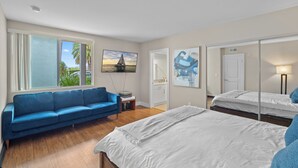 Un dormitorio moderno con una cama, un sofá azul y un ventanal grande.