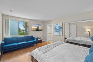 A modern bedroom with a bed, a blue sofa, and a large window.
