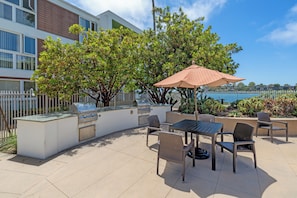 An outdoor patio with a grill, seating, and a view of the water.