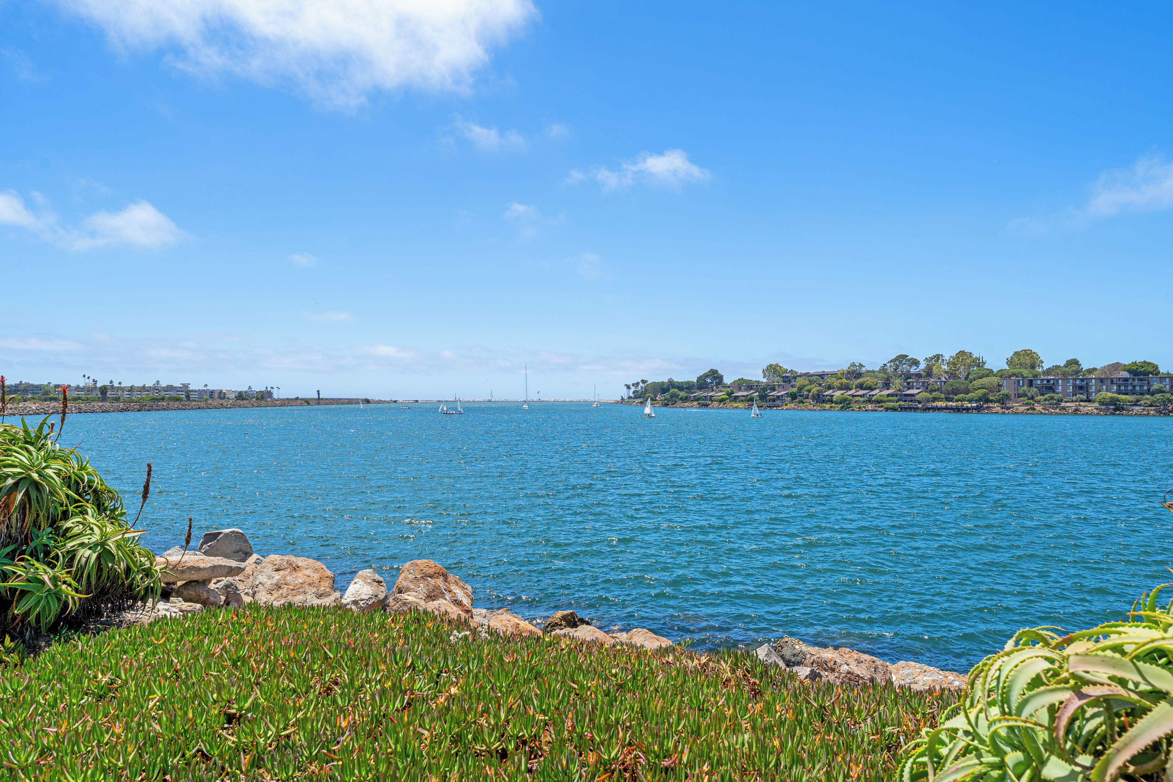 A coastal landscape with a clear sky, calm sea, and rocky shoreline.