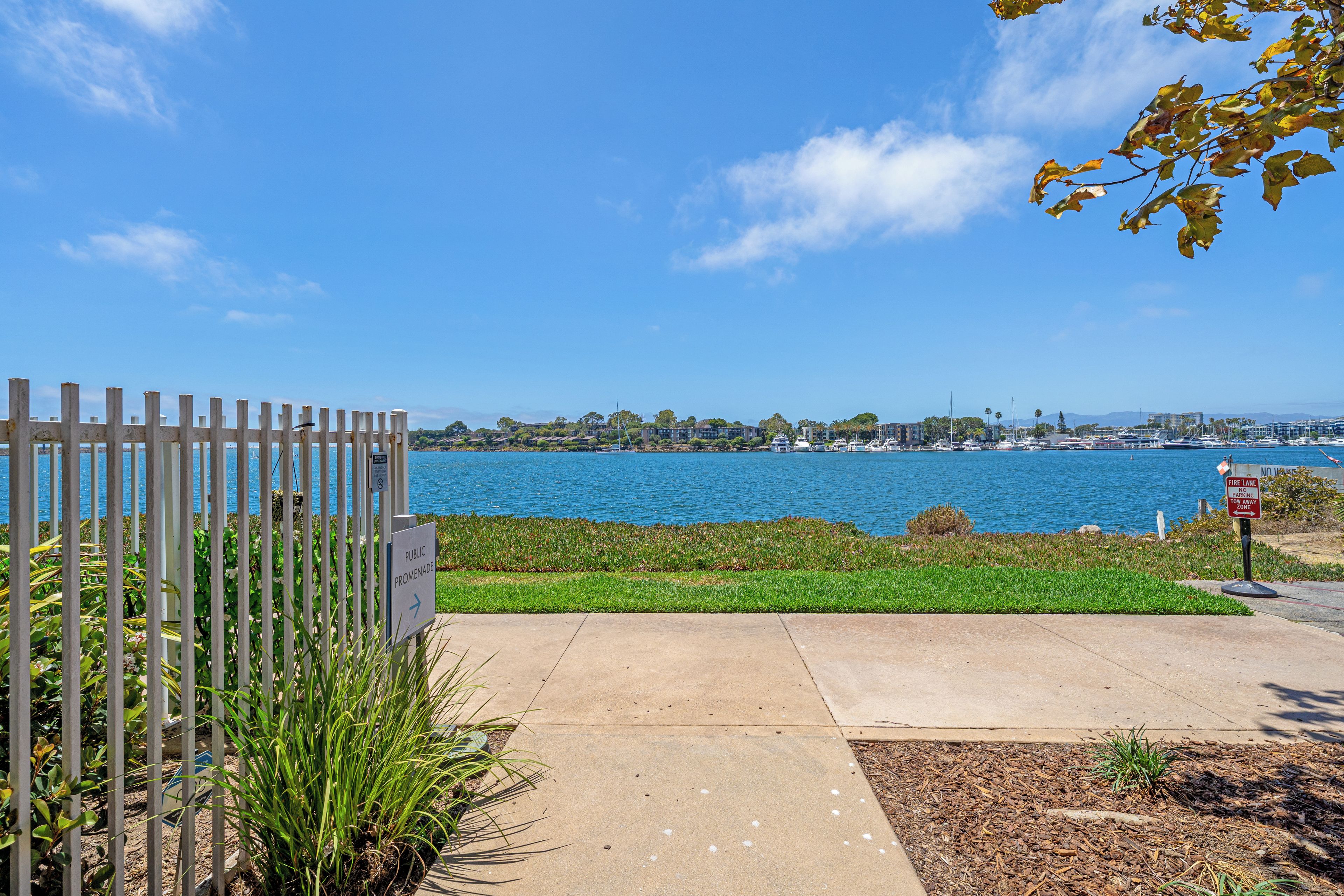 A waterfront promenade with a view of the sea and buildings across the water.
