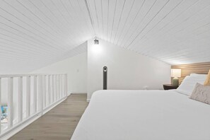 A bedroom with a sloped ceiling, a bed, a nightstand, and a lamp. - ~NEW~ Exclusive Beach Loft ~Turtle Bay Golf Course (Kahuku)
