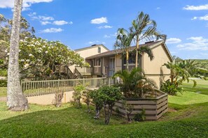 A two-story house with a balcony, surrounded by a fenced yard and tropical plants. - ~NEW~ Exclusive Beach Loft ~Turtle Bay Golf Course (Kahuku)