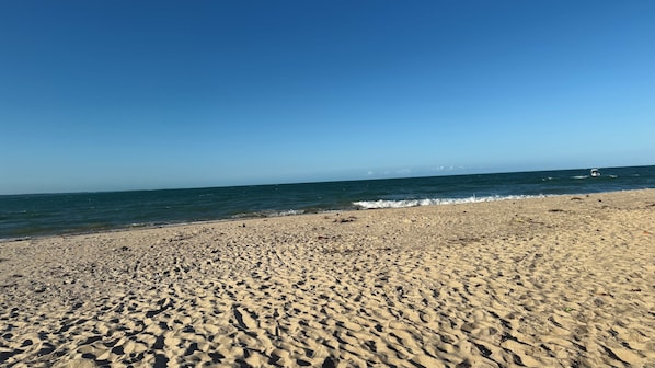 A sandy beach with gentle waves and a clear sky.
