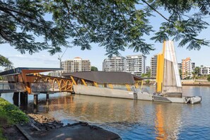 A waterfront bridge with a pedestrian walkway, a concrete structure, and a backdrop of high-rise buildings. - New Farm Hideaway With Courtyard - 2bed-1bath-1car (Brisbane)