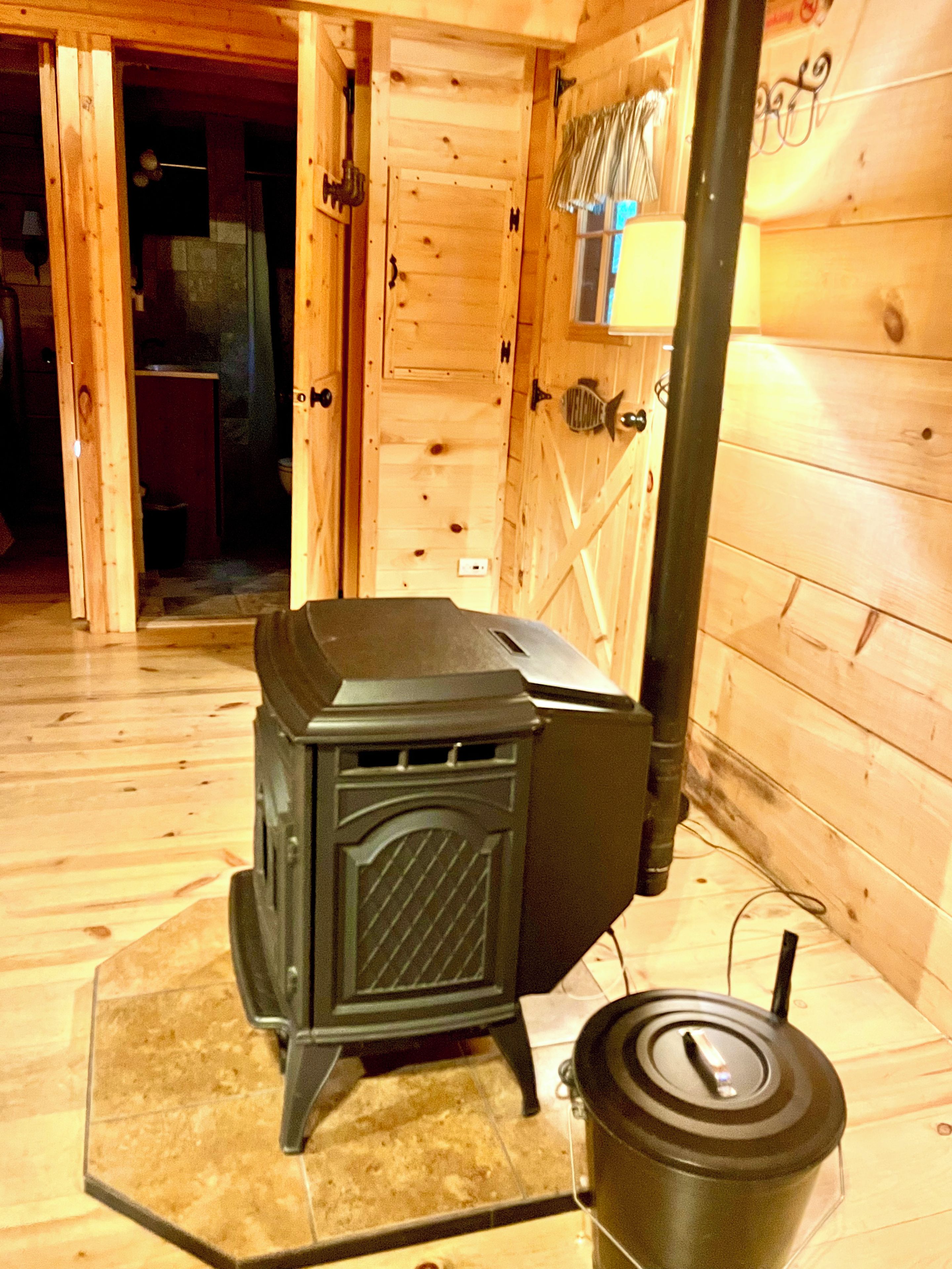 A wood-burning stove in a cabin with a tiled floor and wooden walls.