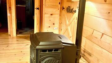 A wood-burning stove in a cabin with a tiled floor and wooden walls.