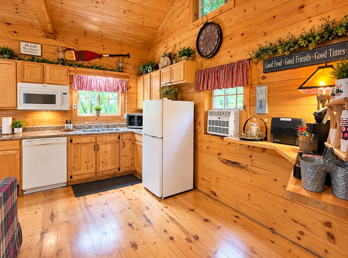 Une cuisine rustique, située dans une cabane en bois, équipée d’un four à micro-ondes, d’un réfrigérateur et de meubles de rangement en bois.