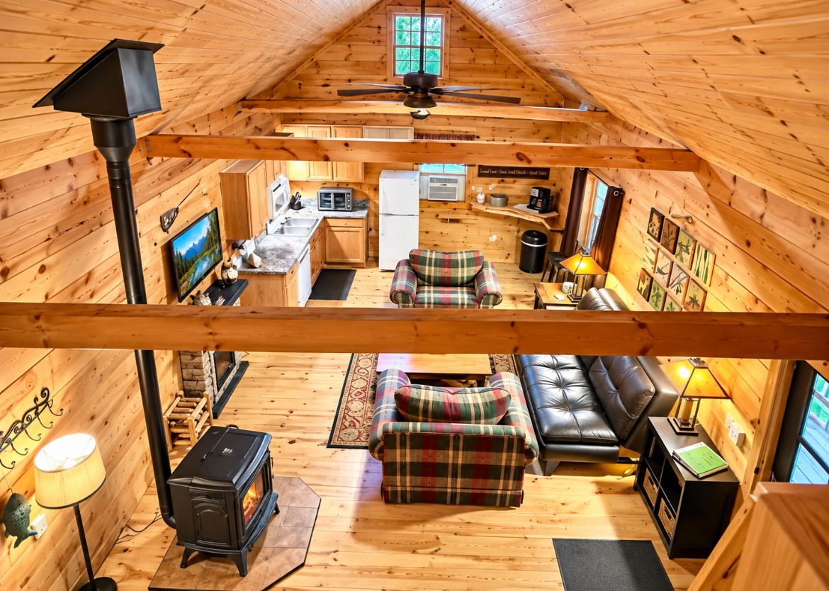 A cozy cabin interior with a fireplace, a sofa, a dining area, and a kitchen.