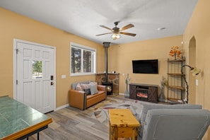 A living room with a fireplace, a sofa, a television, and a ceiling fan. - Luxury Estate with Indoor heated Pool, Spa & Casita (Flagstaff)