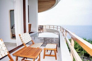 Ein Balkon mit Holztisch und -stühlen, einer gepolsterten Bank und Blick aufs Meer.