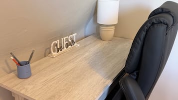 A corner desk with a lamp, a sign reading 'GUEST,' and a cup with writing utensils.