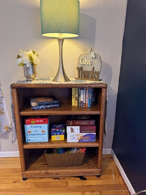 A wooden side table with a lamp, a 'Give Thanks' sign, and a vase of flowers.