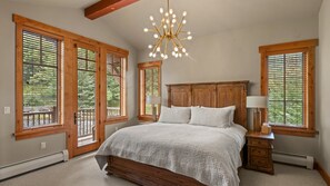 Ein Schlafzimmer mit einem großen Bett, einem Holzkopfteil und mehreren Fenstern mit Jalousien.