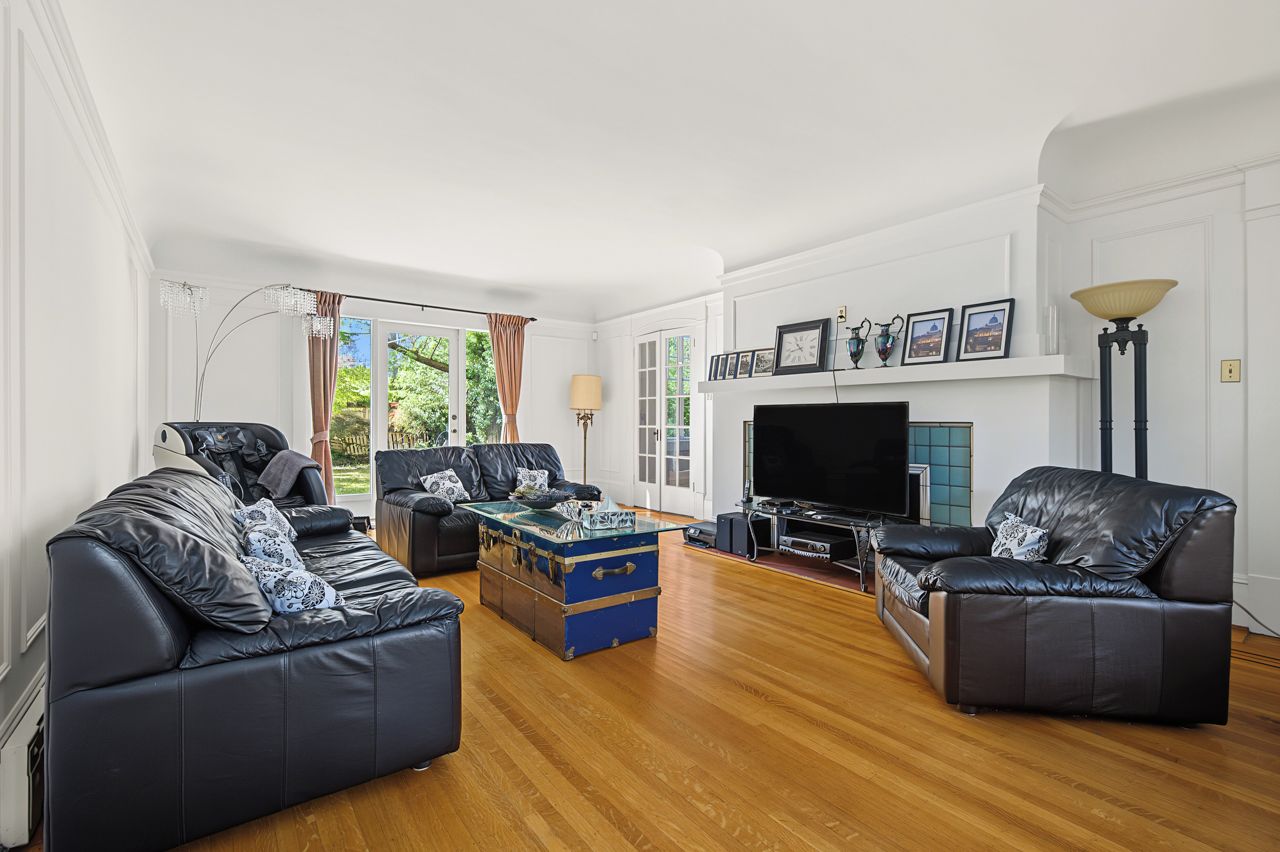 A living room with leather sofas, a blue trunk, a flat-screen TV, and a fireplace.