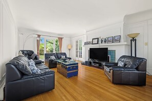 Una sala de estar con sofás de cuero, un baúl azul, un televisor de pantalla plana y una chimenea.