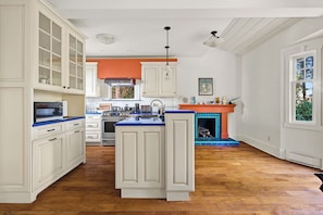 A kitchen with white cabinetry, a blue countertop island, and a built-in fireplace. - Shaughnessy Classic Private Room (Vancouver)