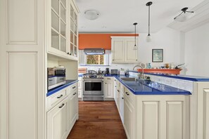 A kitchen with white cabinetry, a blue countertop, and a stainless steel oven.