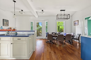 A kitchen with white cabinetry, a blue countertop, and a dining area with a table and chairs. - Shaughnessy Classic Private Room (Vancouver)