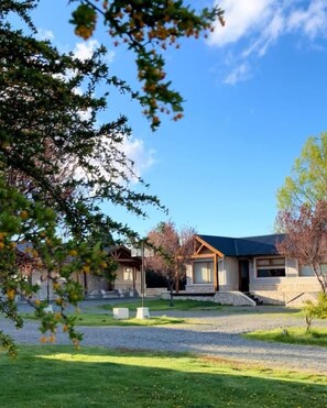A residential property with a well-maintained lawn, a gravel driveway, and a clear blue sky.