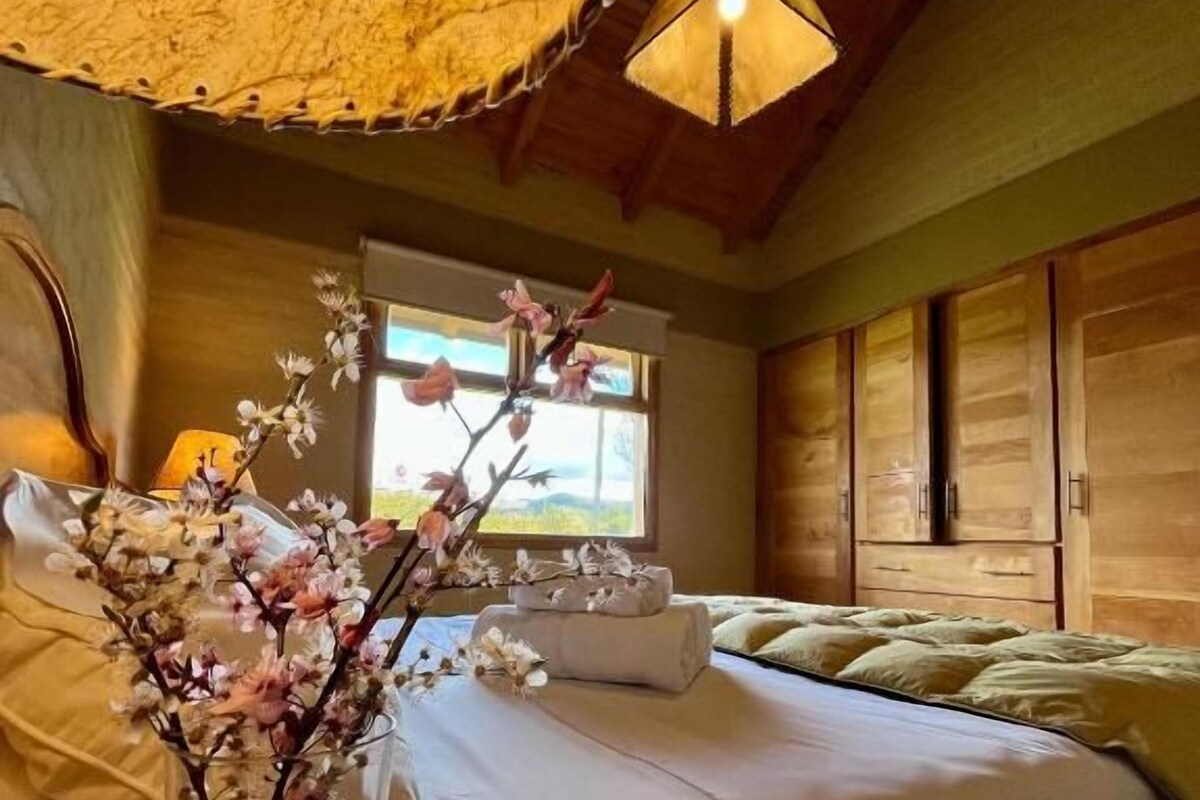 A bedroom with a bed, a vase with flowers, and wooden furniture.