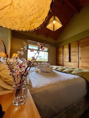 A bedroom with a bed, a vase with flowers, and wooden furniture. - Hostería y Cabañas Land Park (Junín de los Andes)