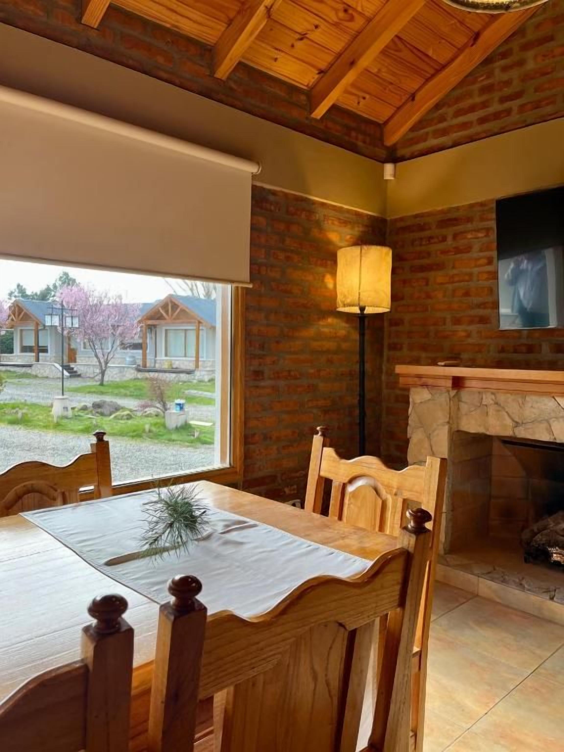 A dining area with a brick wall, a fireplace, and a view of the outside.