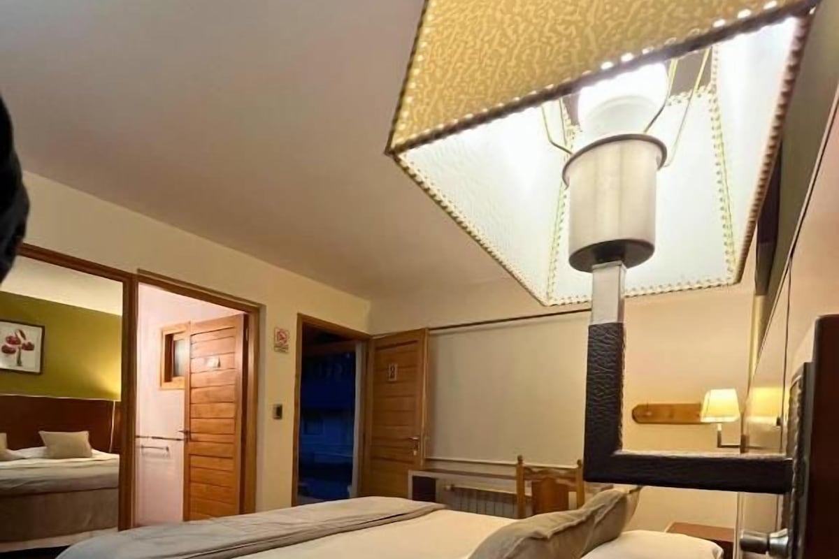 A hotel room with a bed, bedside table, lamp, and a mirror.