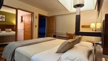 A hotel room with a bed, bedside table, lamp, and a mirror.