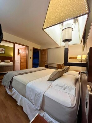 A hotel room with a bed, bedside table, lamp, and a mirror.
