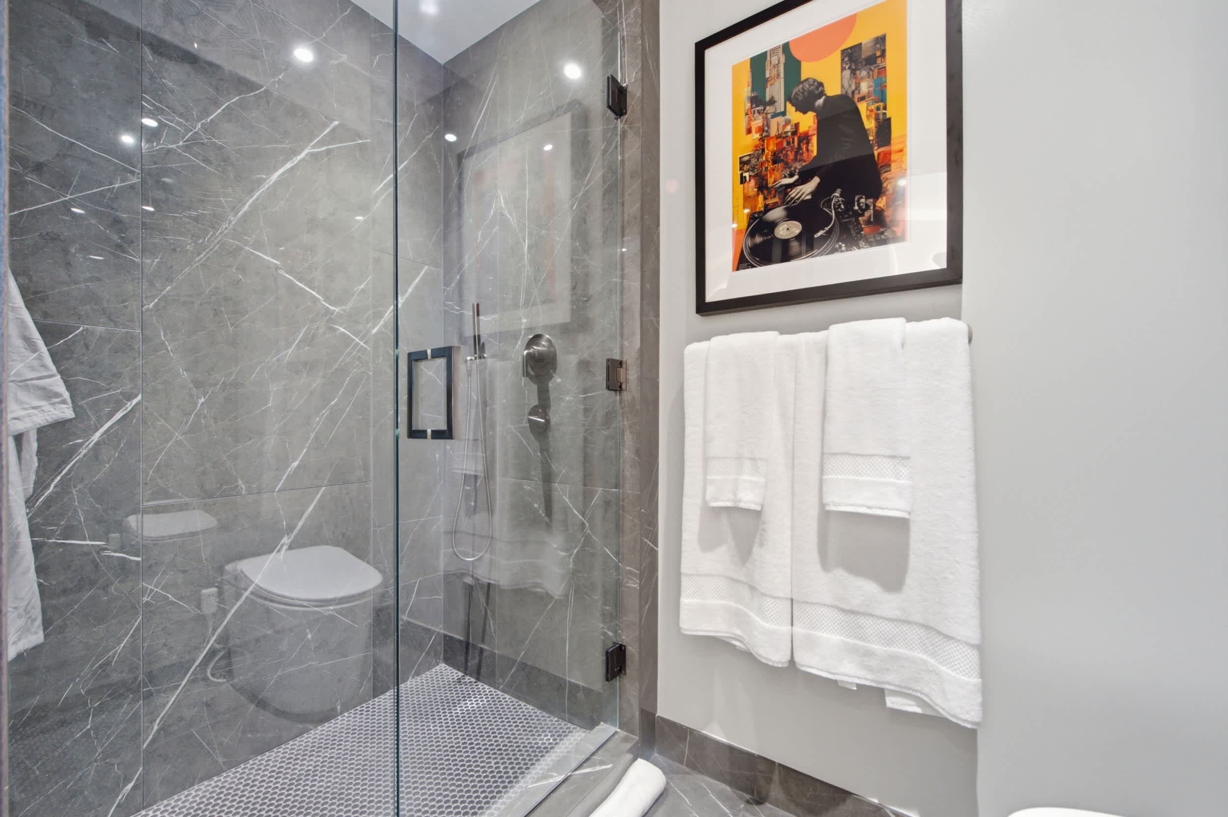 Ein modernes Badezimmer mit einer Duschkabine, einer Toilette und einem gerahmten Bild an der Wand.