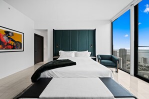 Ein modernes Schlafzimmer mit einem großen Bett, Blick auf die Stadt und einem Bild an der Wand.
