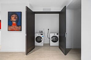 A laundry room with two washing machines, a dryer, and a vent on the ceiling. - Luxury Sky Penthouse Panoramic Views Rooftop Pool (Miami)
