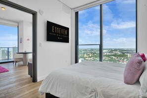 A modern hotel room with a large bed, a view of the city, and a sign for E11EVEN HOTEL & RESIDENCES MIAMI. - E11EVEN 48th Floor Residence with City Views (Miami)