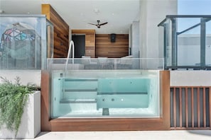 A modern outdoor hot tub with a wooden deck, glass enclosure, and a ceiling fan. - Stunning Miami Studio with City Views at E11EVEN (Miami)
