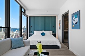 A modern hotel room with a large bed, a sofa, a view of the city, and a door to the bathroom. - Luxury High Floor Water View | Miami Rooftop Pool (Miami)